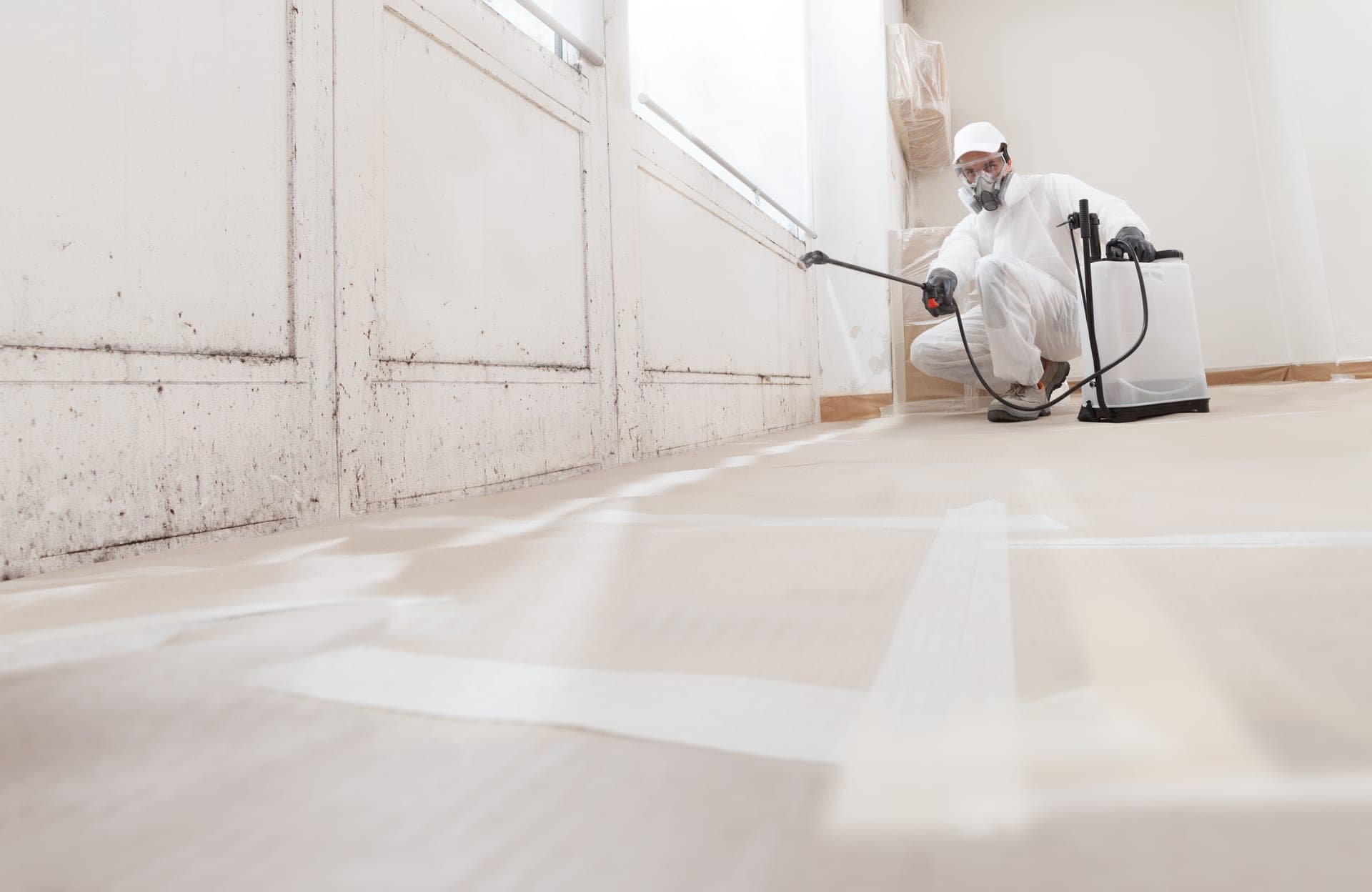 A remediation technician in protective gear treating a room